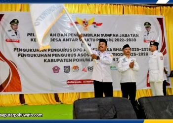 Sirwan Mohi, S.AP mengibarkan bendera pataka DPC APDESI Kabupaten Pohuwato saat pelantikan dan pengukuhan di Gedung Panua Pohuwato, Senin (10/11/2025).