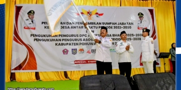 Sirwan Mohi, S.AP mengibarkan bendera pataka DPC APDESI Kabupaten Pohuwato saat pelantikan dan pengukuhan di Gedung Panua Pohuwato, Senin (10/11/2025).
