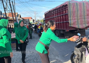 Sejumlah ibu-ibu berseragam hijau bersama personel TNI dari Kodim 1313/Phw tampak berdiri di tepi jalan membagikan takjil kepada pengendara yang melintas